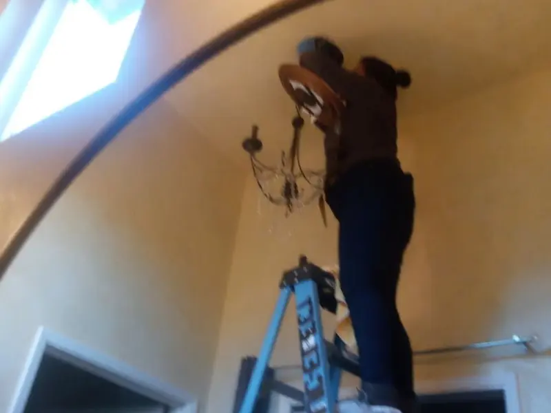 Electrician installing a chandelier in a Liberty Triangle residence